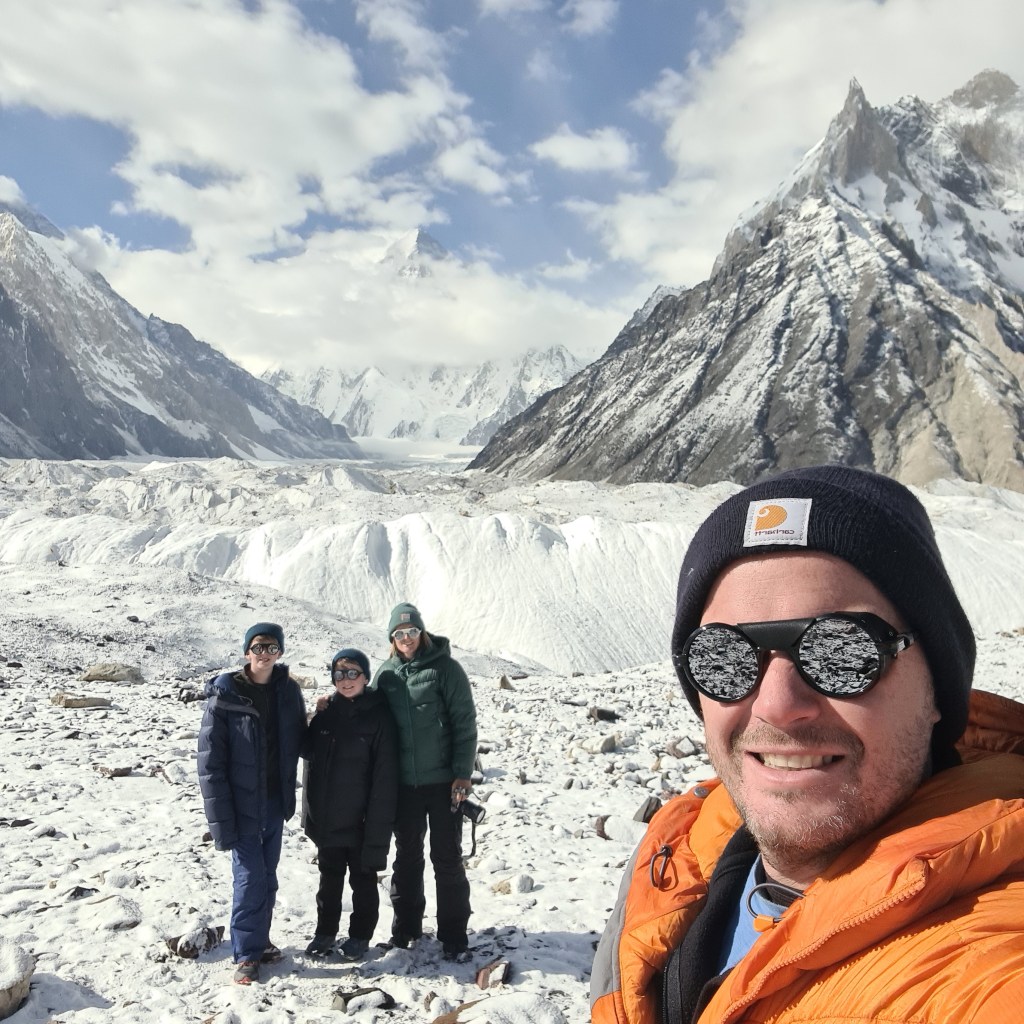 Family of 4 at concordia camp wearing there thick feather down jackets and keeping warm which is essential for a family hiking in Pakistan towards K2